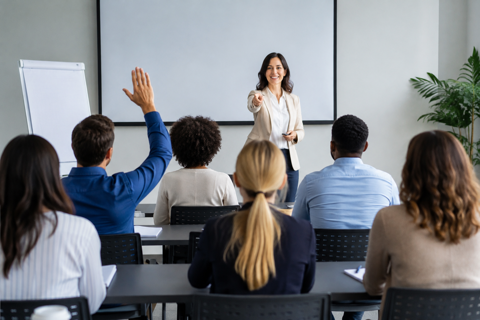 Training Topics Leaders Skip shown in a professional employee training class with an instructor calling on an employee who has raised their hand.