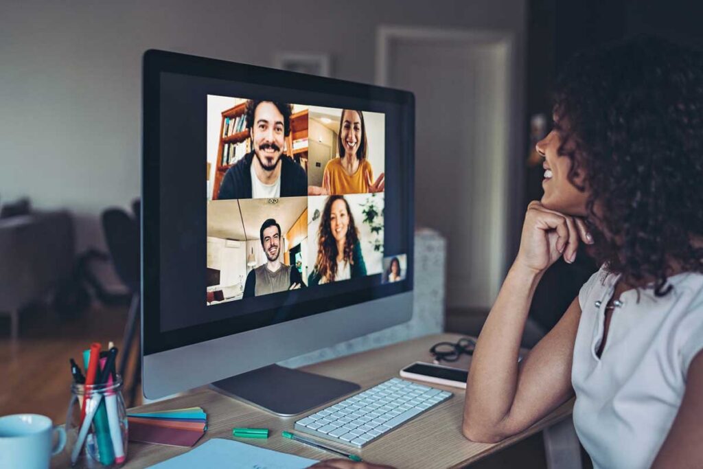 A woman facing a computer screen with four individuals in the middle of a virtual meeting to symbolize how to keep remote employees engaged.