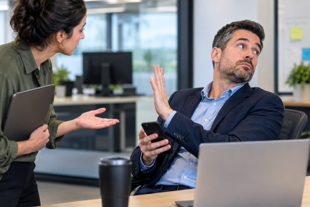 Manager dismissing an employee who is trying to ask a question in an office to signify manager engagement.
